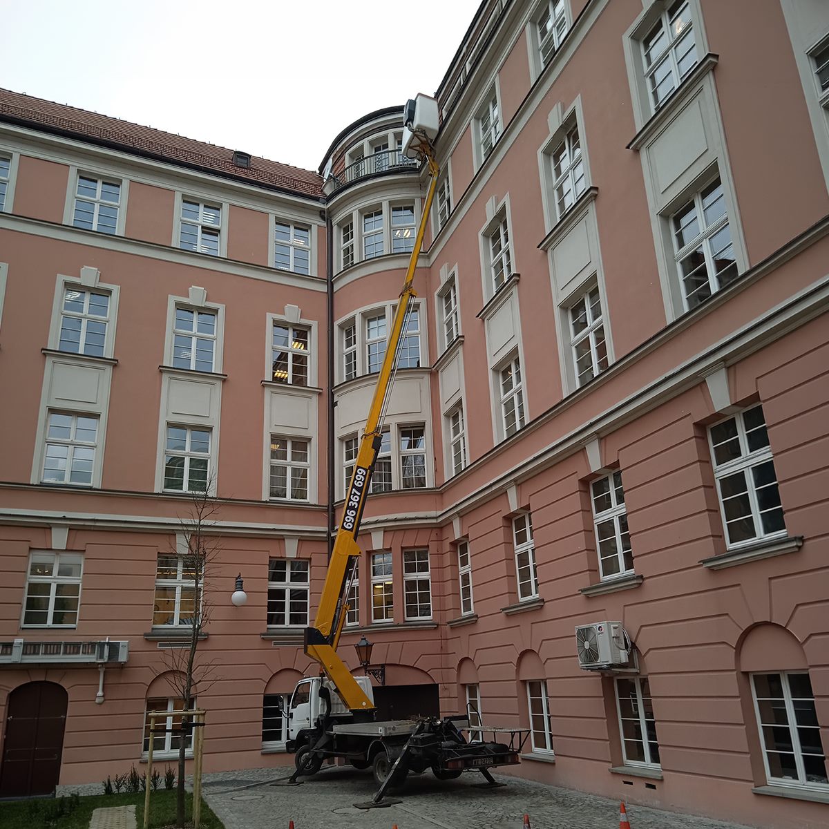 Podnośnik koszowy na dziedzińcu kamienicy, kosz przy dachu